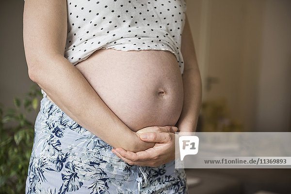 Mittelteil einer schwangeren Frau  die ihren Bauch hält