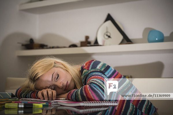 Erschöpfter Schüler  der bei den Hausaufgaben im Wohnzimmer schläft