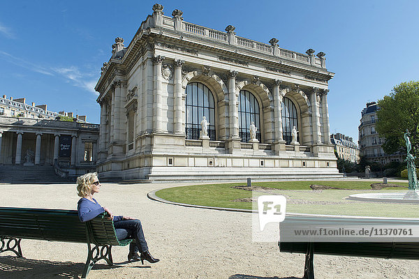 Frankreich. Paris  16. Bezirk. Frau sitzt auf einer Bank vor dem Galliera-Palast  dem Modemuseum der Stadt Paris. Architekt: Leon Ginain (1894).