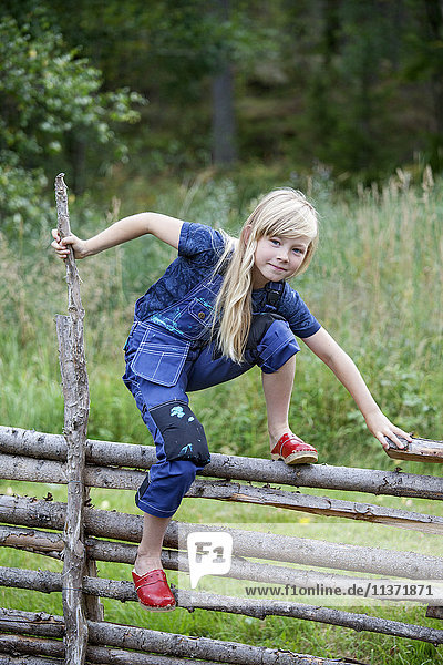 Mädchen klettert auf Holzzaun