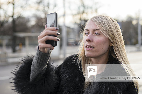 Junge Frau fotografiert mit einem Mobiltelefon