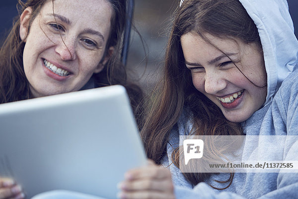 Mutter und Mädchen im Teenageralter benutzen ein digitales Tablet