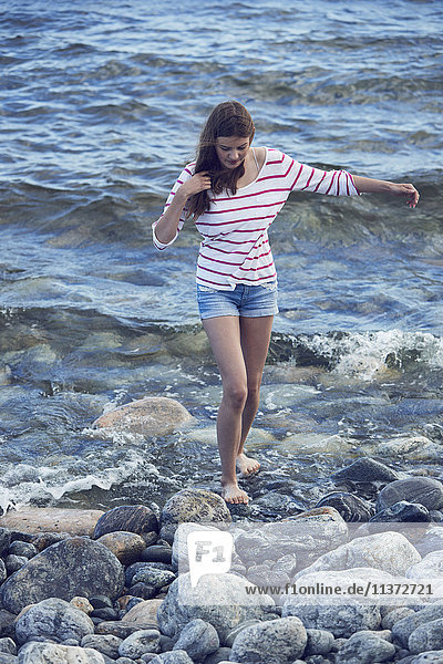 Frau läuft auf Steinen im Meer