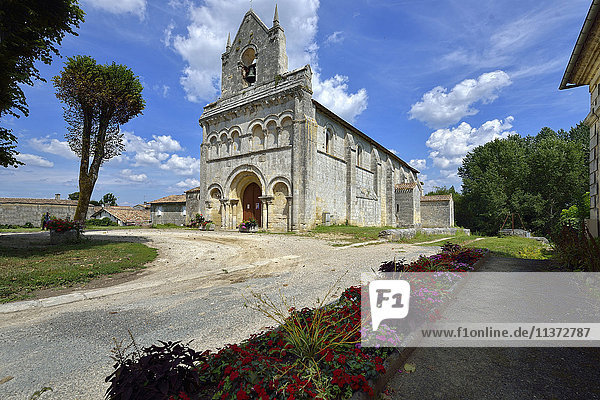 Frankreich  Gironde  Kirche von Tauriac  unter blauem Himmel. Blumenbeet im Vordergrund