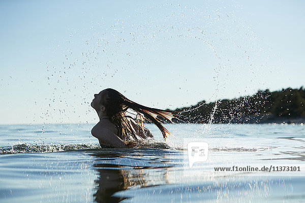 Mädchen wirft Haare ins Wasser