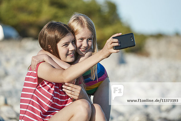 Mädchen nehmen Selfie am Strand
