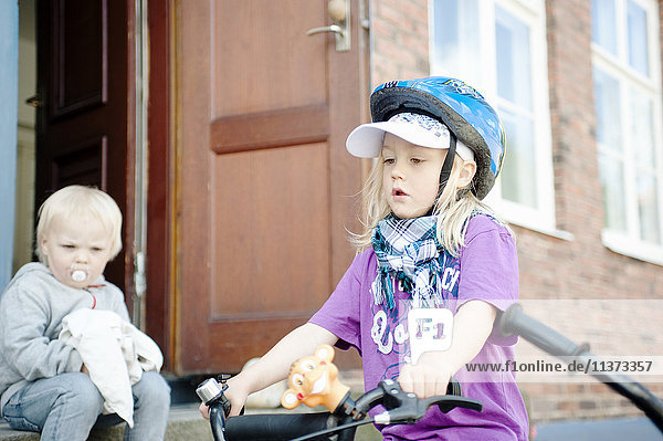Boy watching brother wearing safety helmet riding bike