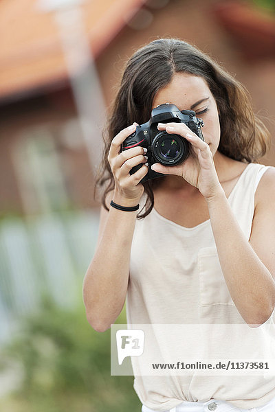 Junge Frau beim Fotografieren mit Kamera