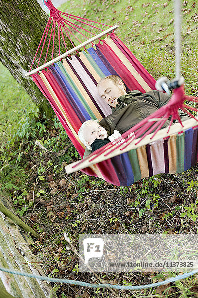 Man resting in hammock with son
