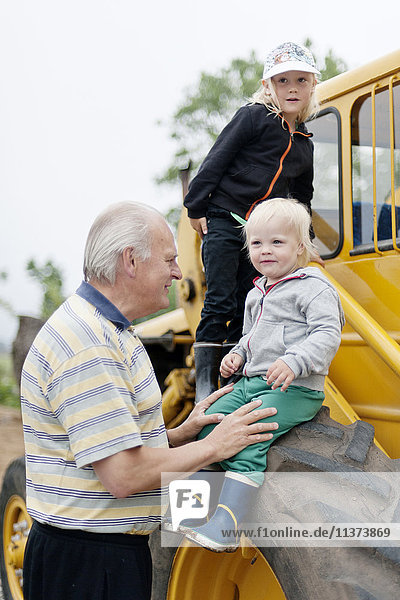 Grandfather with grandchildren by tractor