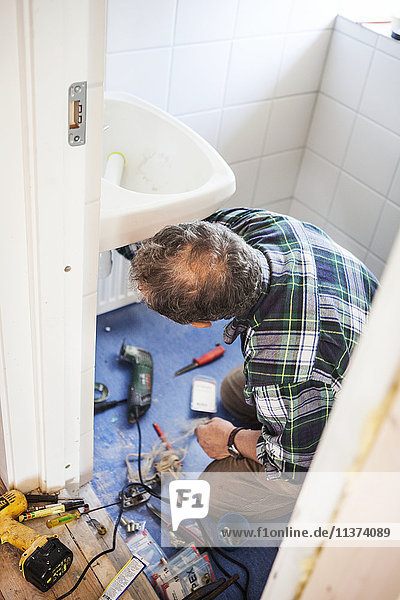 Mann repariert Waschbecken im Bad