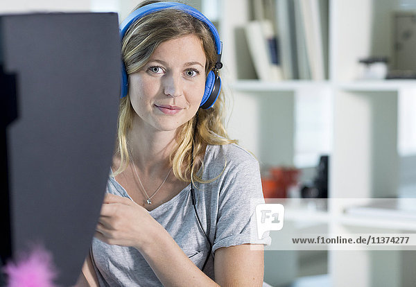Woman using computer with headphones on