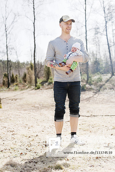 Father holding baby son  standing in forest
