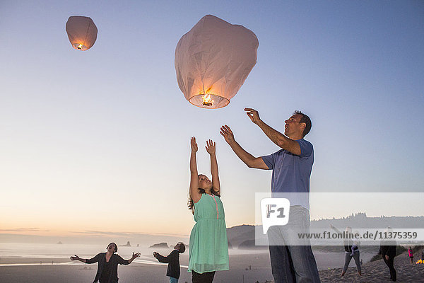 Kaukasischer Vater und Tochter fliegen Laterne Ballon am Strand