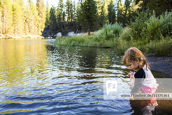 Caucasian girl crouching in river