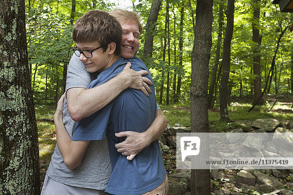 Kaukasischer Vater und Sohn umarmen sich im Wald