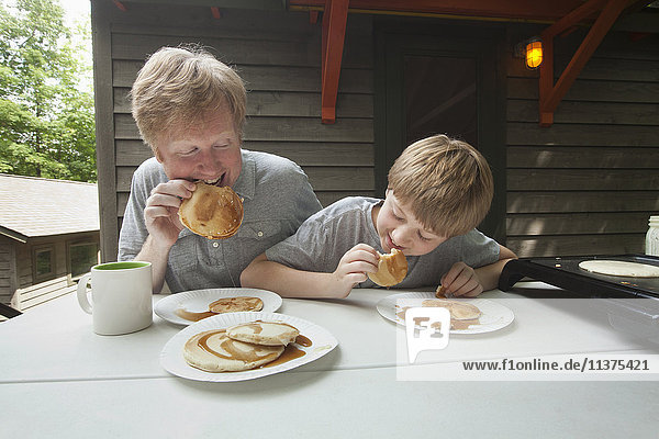 Caucasian father and son eating pancakes outdoors