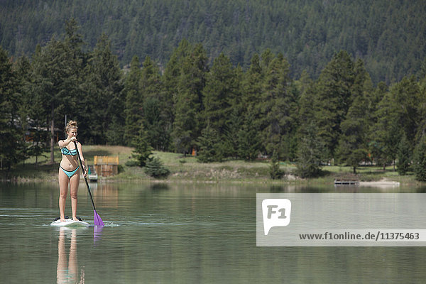 Kaukasisches Mädchen paddelt auf einem See