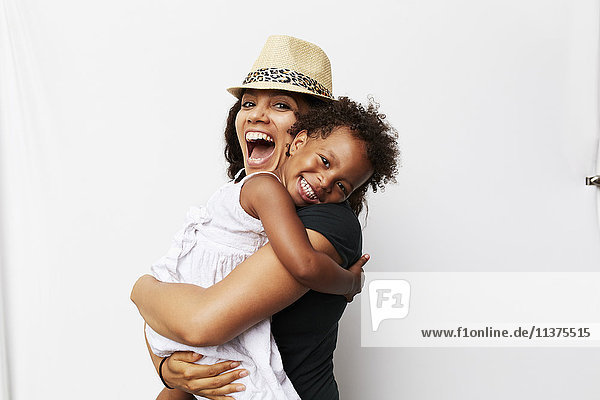 Lächelnde gemischtrassige Frau  die ihre Tochter umarmt