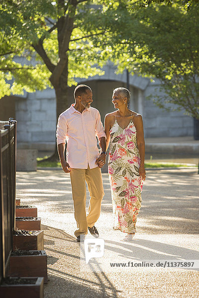 Black couple holding hands walking in park