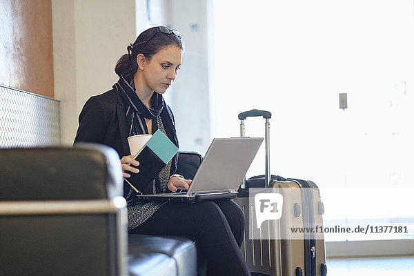Hispanische Frau mit Reisepass und Laptop auf dem Flughafen