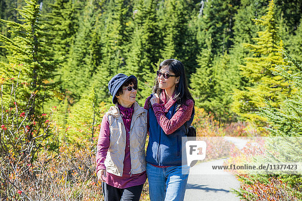 Older Japanese mother and daughter walking on nature path