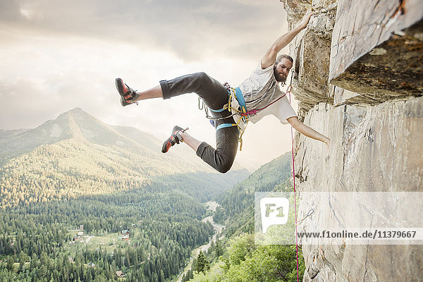 Caucasian man hanging from rock while climbing