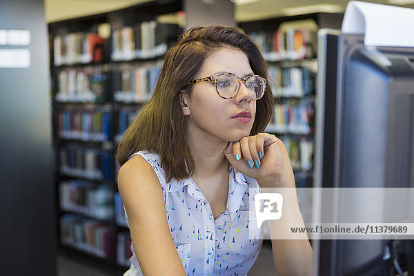 Gemischtrassiges Mädchen benutzt Computer in Bibliothek