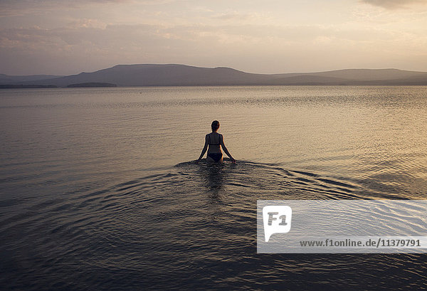 Silhouette einer in einem See watenden kaukasischen Frau