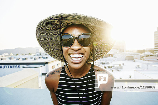 Schwarze Frau mit Sonnenhut und Sonnenbrille auf dem Dach