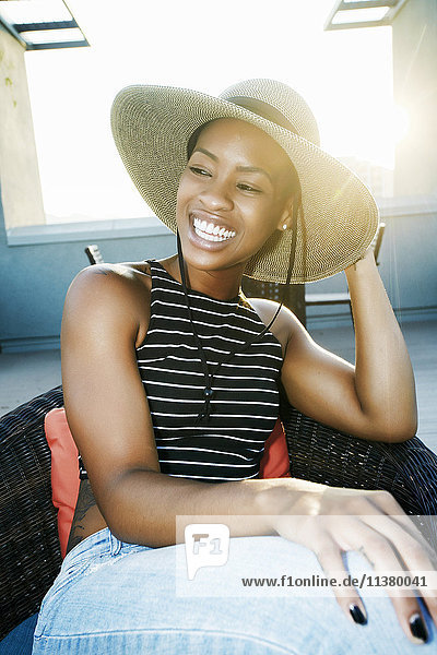 Black woman wearing sun hat on rooftop
