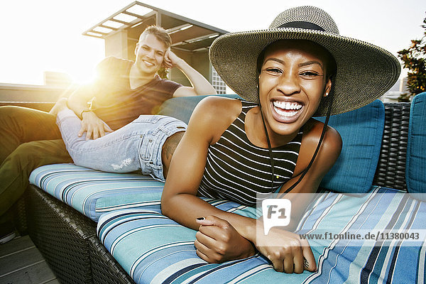 Portrait of smiling couple on rooftop sofa