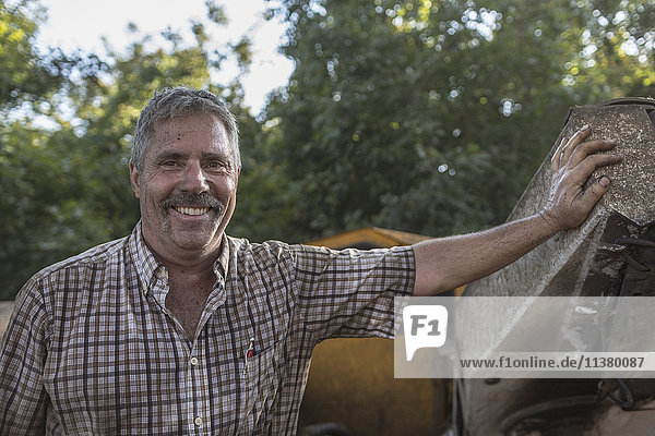 Kaukasischer Mann lehnt an Traktor