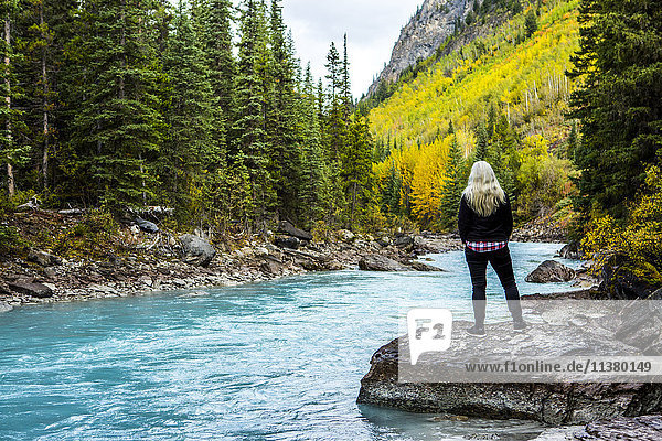 Kaukasische Frau steht auf einem Felsen in der Nähe eines Gebirgsflusses
