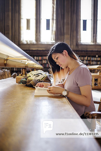 Chinese woman sitting in library reading book