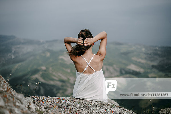 Caucasian woman sitting on rock overlooking landscape