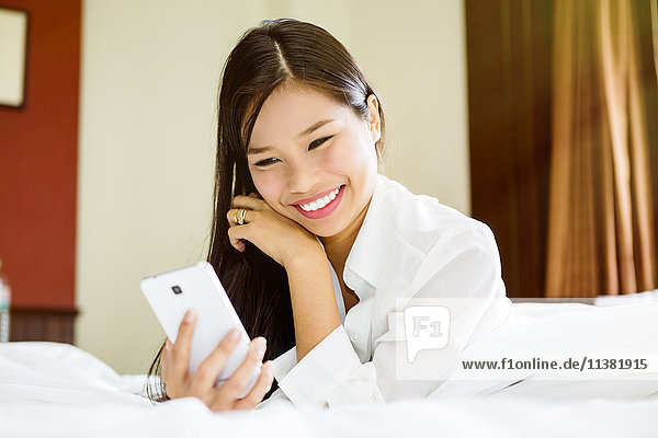 Smiling Asian teenage girl texting on cell phone