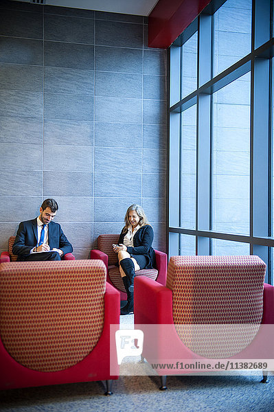 Geschäftsmann und Geschäftsfrau sitzen in einer Bürolounge