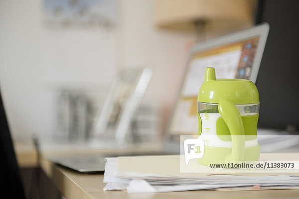 Sippy cup on file folder near laptop