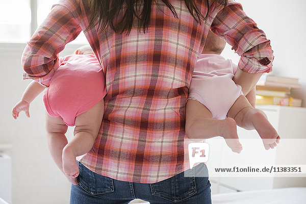 Caucasian mother holding twin baby daughters