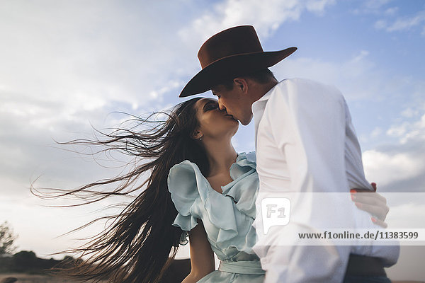 Caucasian cowboy kissing woman in wind