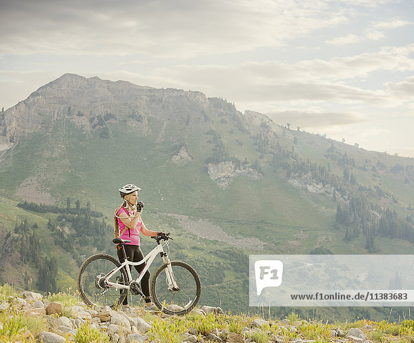 Caucasian woman with mountain bike drinking from backpack