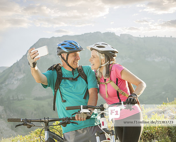 Kaukasisches Paar mit Mountainbikes posiert für Handy-Selfie