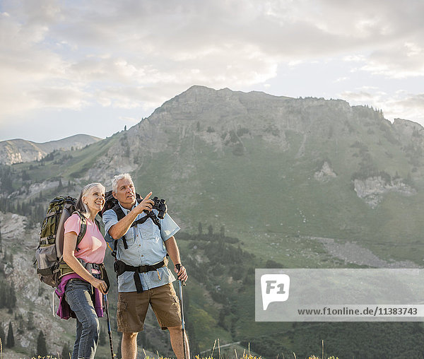 Caucasian couple with binoculars hiking on mountain