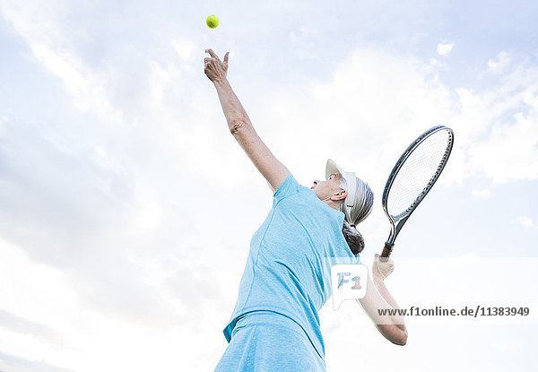 Kaukasische Frau serviert Tennisball