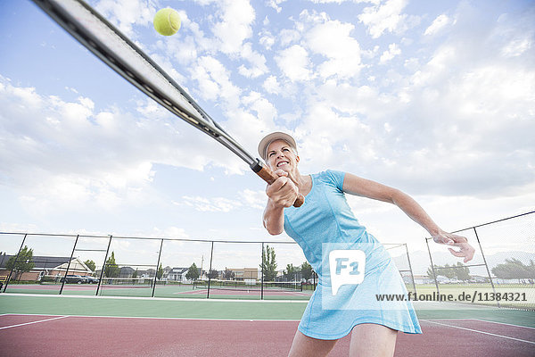 Caucasian woman hitting tennis ball