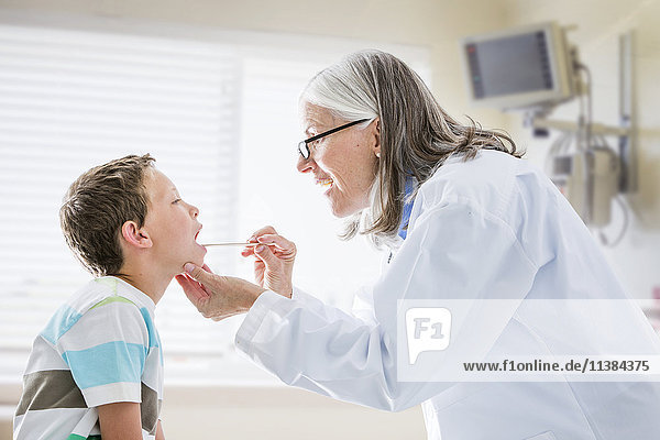 Caucasian doctor examining mouth of boy
