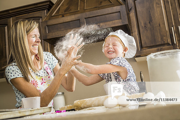 Caucasian mother and daughter having food fight with flour