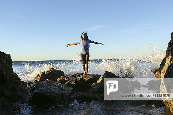 Asiatische Frau steht auf einem Felsen am Strand