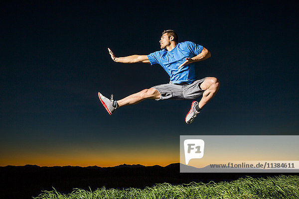 Caucasian man jumping at sunset